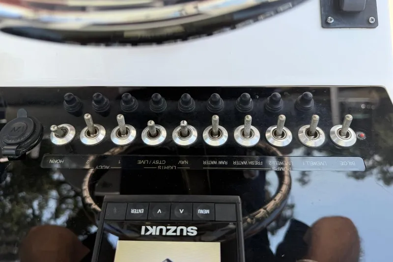Slide: The Image of Control panel of a 2021 Sea Pro 248 Bay boat with toggle switches and Suzuki display. - 10