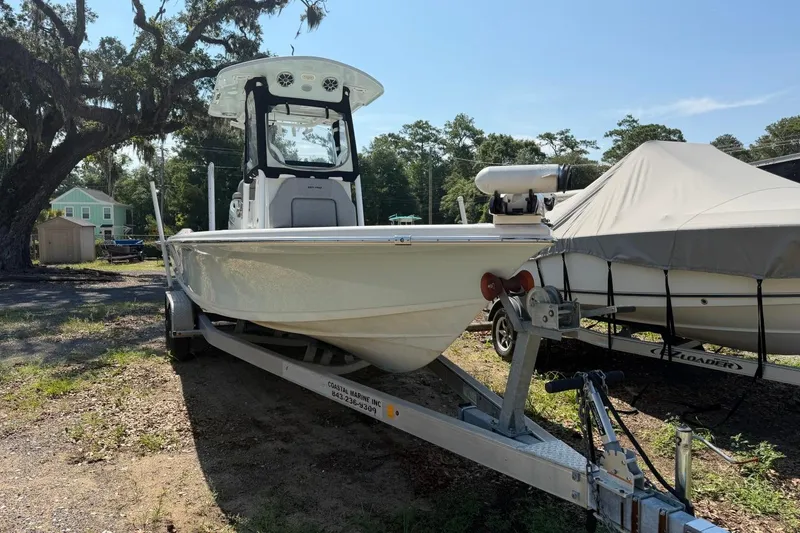 Slide: The Image of 2021 Sea Pro 248 Bay boat on trailer, parked outdoors under a tree. - 3