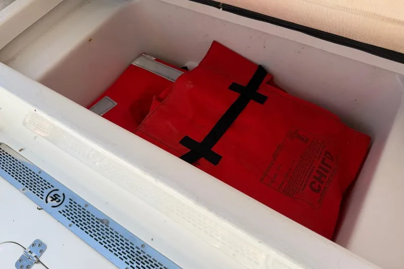 Slide: The Image of Red life jacket stored in a compartment of a 2021 Sea Pro 248 Bay boat. - 22