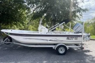 Slide: The Image of 2014 Carolina Skiff JVX18CC boat on trailer, parked outdoors with trees in the background. - 0