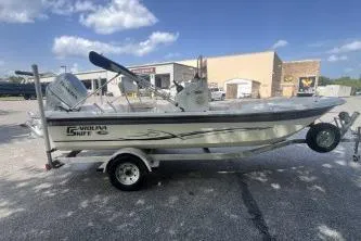 Slide: The Image of 2014 Carolina Skiff JVX18CC boat on trailer, parked outdoors under blue sky. - 2