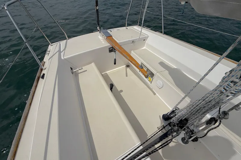 Slide: The Image of 2006 J Boats J/100 sailboat cockpit with wooden tiller and rigging, on calm water. - 28