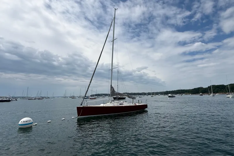 Slide: The Image of 2006 J Boats J/100 sailboat moored in a scenic harbor under a cloudy sky. - 29