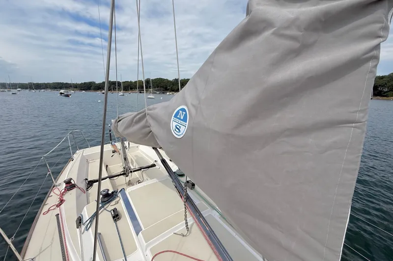 Slide: The Image of 2006 J Boats J/100 sailboat with covered sail, docked in a serene harbor. - 9