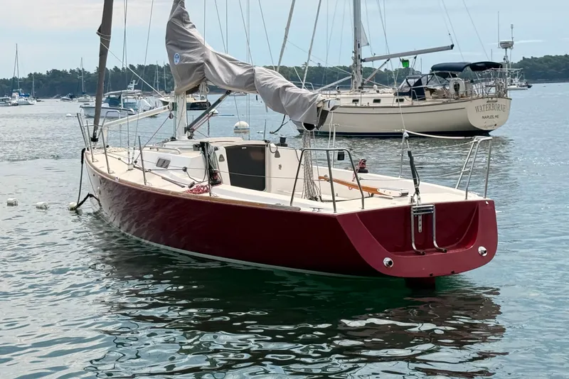 Slide: The Image of 2006 J Boats J/100 sailboat with red hull moored in a calm harbor. - 2