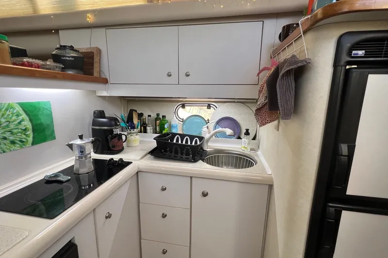 Slide: The Image of Compact kitchen in a 1998 Cruisers Yachts 3650 Aft Cabin, featuring modern appliances and storage. - 37