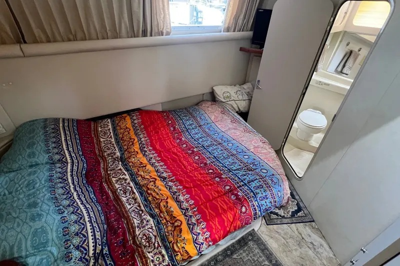 Slide: The Image of 1998 Cruisers Yachts 3650 Aft Cabin interior with colorful bedspread and adjacent bathroom. - 35