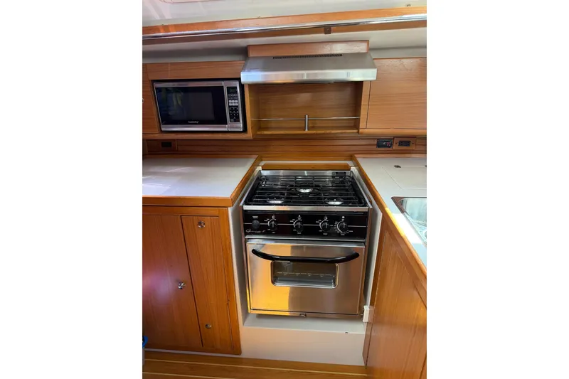 Slide: The Image of Galley kitchen in 2015 Catalina 445 yacht with stove, microwave, and wooden cabinetry. - 54