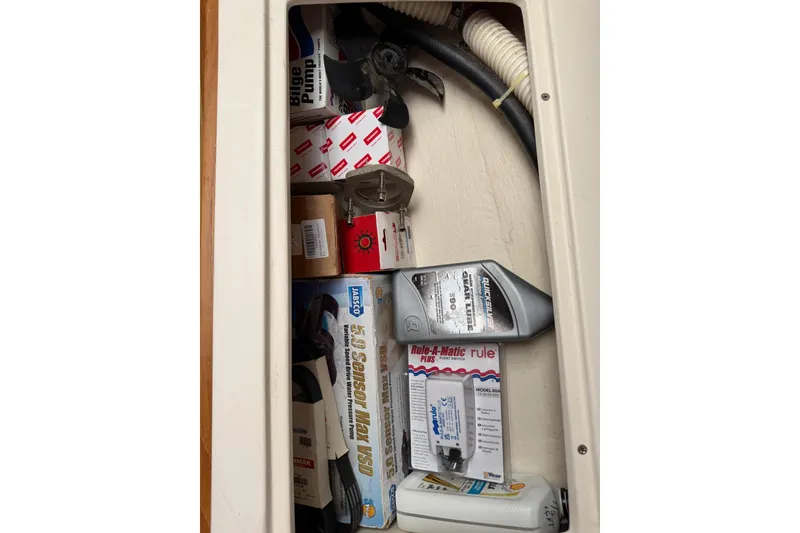 Slide: The Image of Storage compartment with boat maintenance supplies, including bilge pump and oil, in a 2015 Catalina 445. - 56