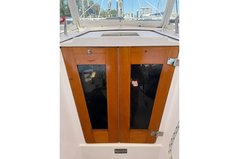 Slide: The Image of Wooden cabin doors on a 2015 Catalina 445 sailboat, with marina background. - 29