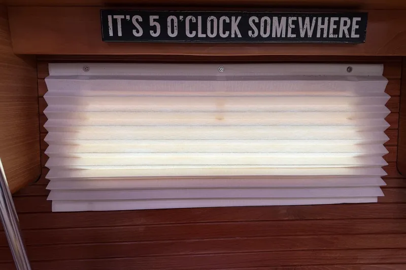 Slide: The Image of Interior of a 2015 Catalina 445 with a humorous "It's 5 o'clock somewhere" sign above a window shade. - 34