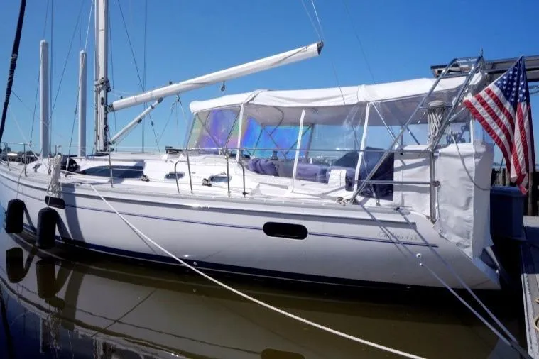The Image of 2015 Catalina 445 sailboat docked with American flag, clear skies. - 0