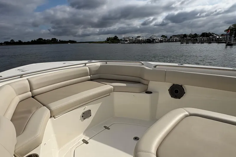 Slide: The Image of 2020 Boston Whaler 330 Outrage boat interior with cushioned seating, on a calm waterway. - 13