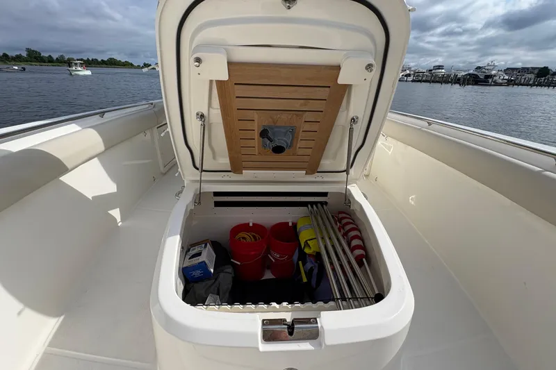 Slide: The Image of Open storage compartment on 2020 Boston Whaler 330 Outrage boat, docked by the water. - 20