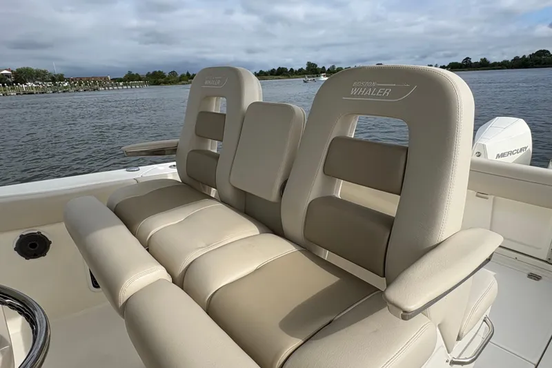 Slide: The Image of 2020 Boston Whaler 330 Outrage boat seating with luxurious beige upholstery on a calm water backdrop. - 9