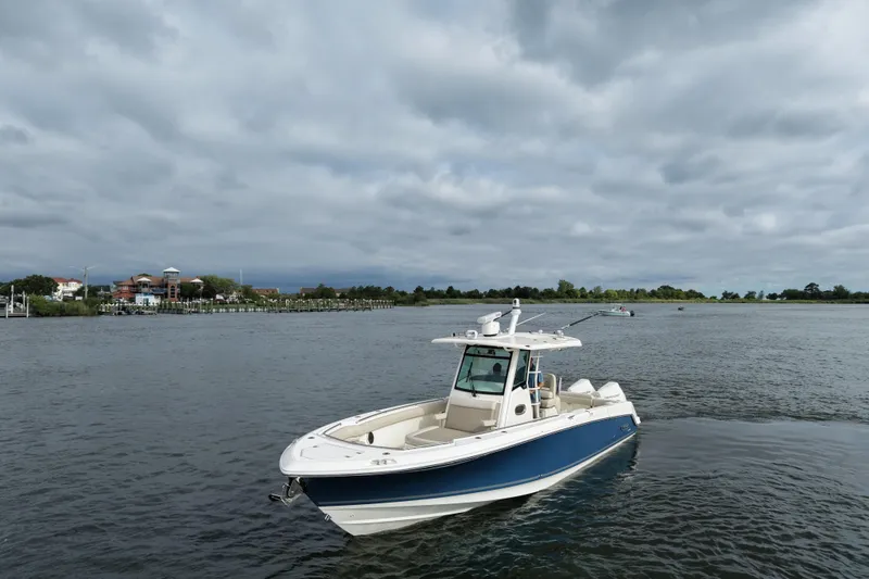 Slide: The Image of 2020 Boston Whaler 330 Outrage boat on a calm river under cloudy skies. - 4