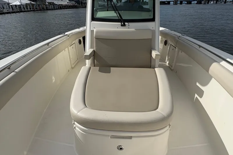 Slide: The Image of 2020 Boston Whaler 330 Outrage boat interior with cushioned seating, docked by the water. - 10