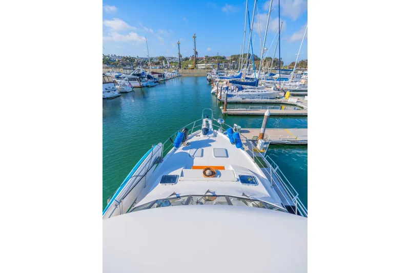 Slide: The Image of 1998 Bayliner 4788 Pilot House Motoryacht docked in a marina under a clear blue sky. - 35