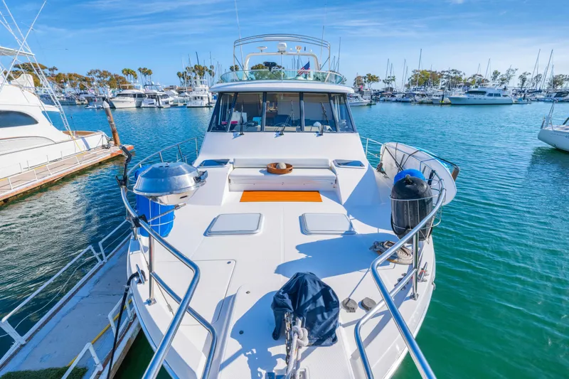 Slide: The Image of 1998 Bayliner 4788 Pilot House Motoryacht docked in a marina under clear blue skies. - 25