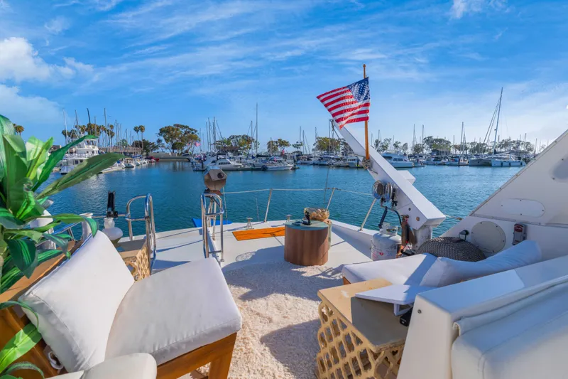 Slide: The Image of 1998 Bayliner 4788 Pilot House Motoryacht docked in a scenic marina with American flag. - 34