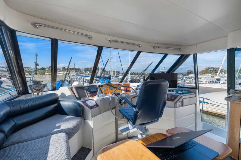 Slide: The Image of 1998 Bayliner 4788 Pilot House Motoryacht interior with helm, seating, and marina view. - 26