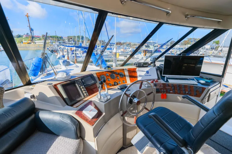 Slide: The Image of 1998 Bayliner 4788 Pilot House Motoryacht helm with marina view, featuring navigation equipment and controls. - 18