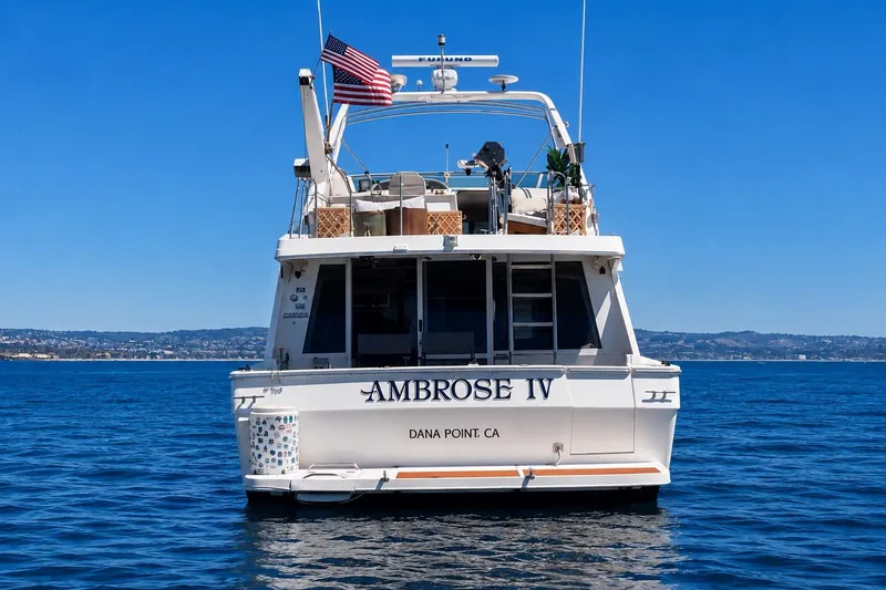 Slide: The Image of 1998 Bayliner 4788 Pilot House Motoryacht on open water, rear view with American flag. - 3
