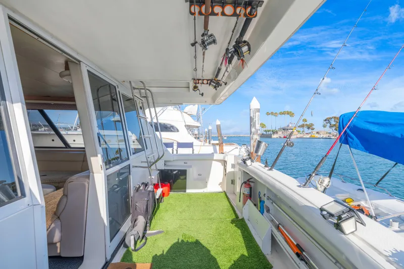 Slide: The Image of 1998 Bayliner 4788 Pilot House Motoryacht deck with fishing gear, docked by blue waters. - 37
