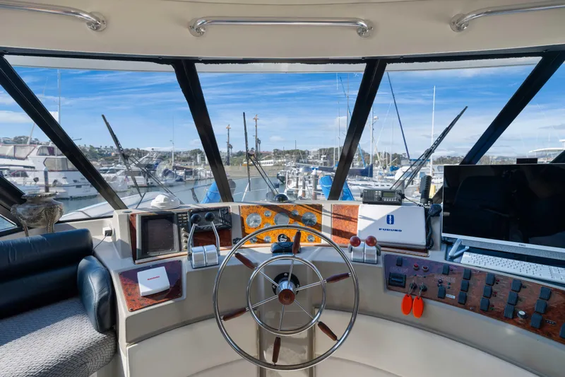 Slide: The Image of Interior view of 1998 Bayliner 4788 Pilot House Motoryacht helm with marina background. - 23