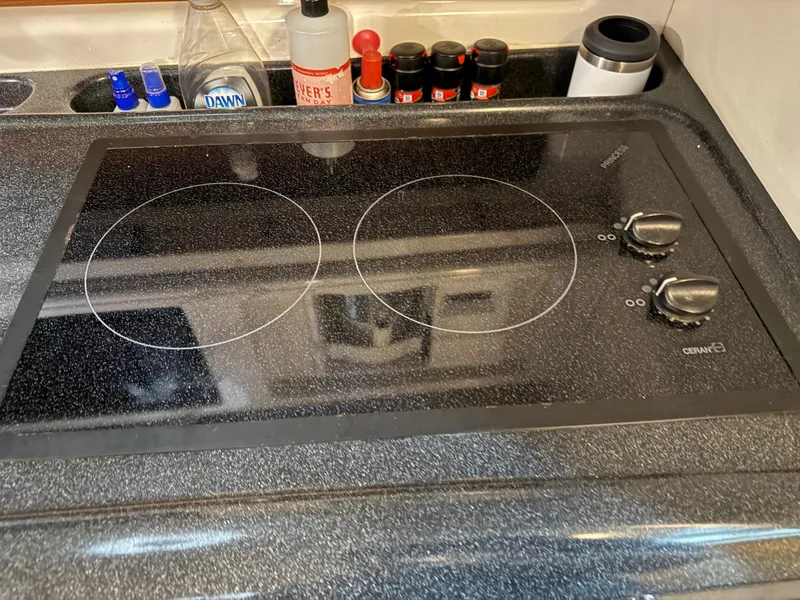 Slide: The Image of Stovetop in 2003 Monterey 302 Cruiser kitchen with spices and cleaning supplies. - 28