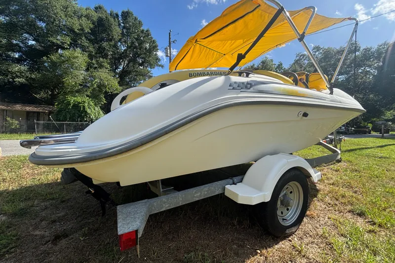Slide: The Image of 2004 Sea-Doo Sportster LE DI boat with yellow canopy on trailer, parked on grass. - 2