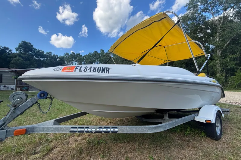 Slide: The Image of 2004 Sea-Doo Sportster LE DI boat with yellow canopy on trailer, parked outdoors. - 8