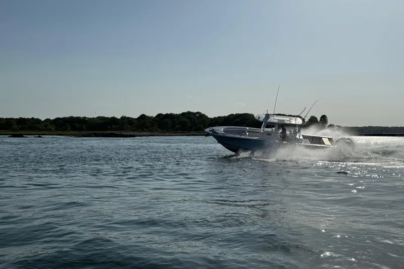 Slide: The Image of 2020 Southport 33 FE boat cruising on a sunny day near a forested shoreline. - 16
