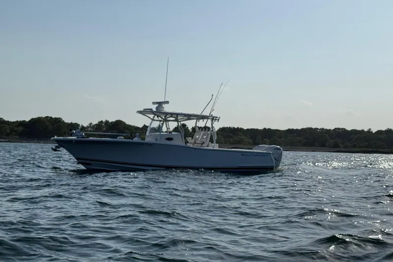 The Image of 2020 Southport 33 FE boat cruising on a calm sea near a forested shoreline. - 0