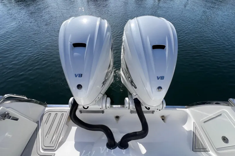 Slide: The Image of Twin V8 outboard engines on a 2020 Southport 33 FE boat, docked on calm water. - 33
