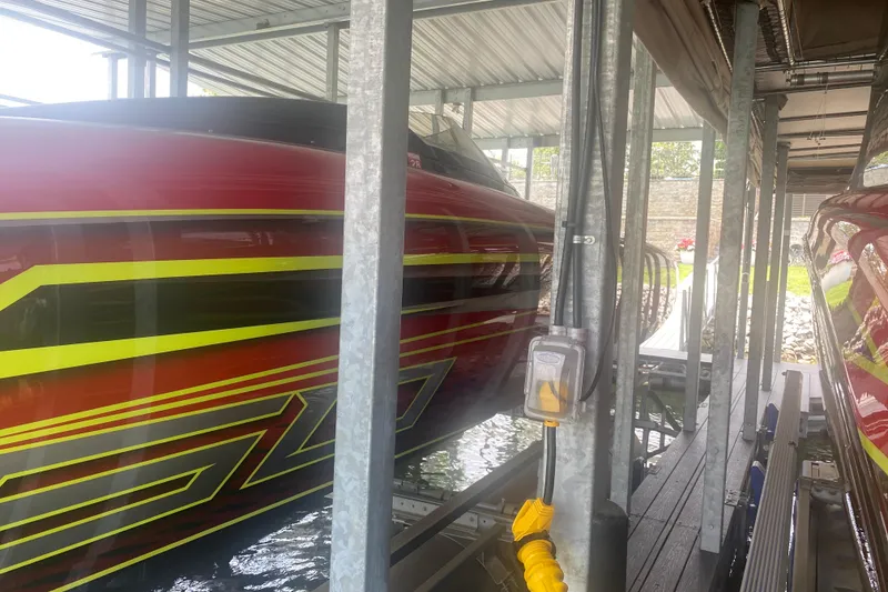 Slide: The Image of 2021 Doug Wright P360 boat with vibrant red and yellow design in a covered dock. - 9