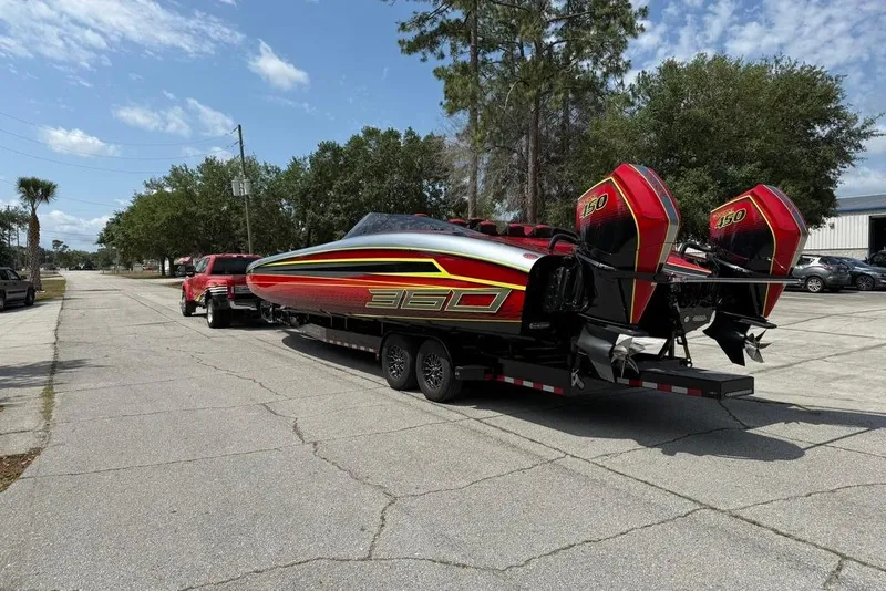 Slide: The Image of 2021 Doug Wright P360 powerboat on trailer, vibrant red and black design, parked on street. - 2