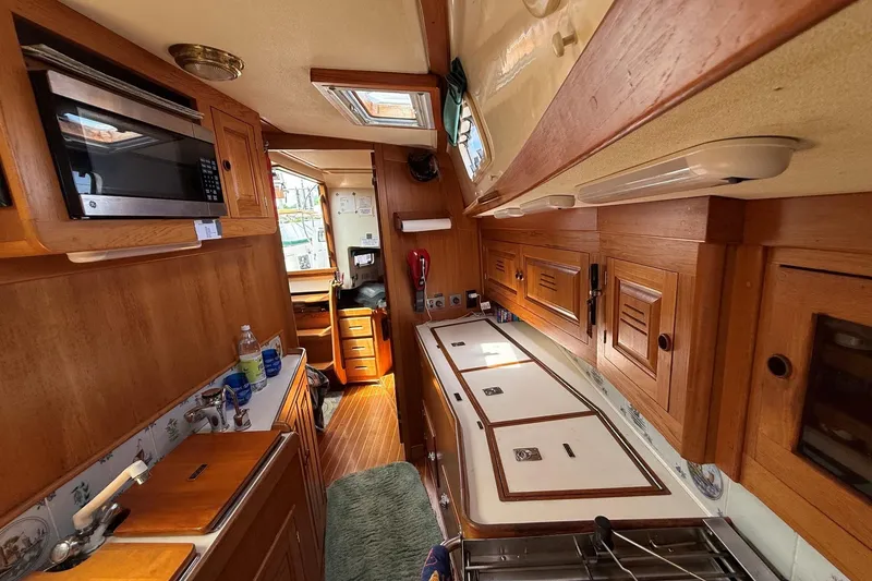 Slide: The Image of Interior of 1993 Tartan 4600 sailboat with wooden cabinetry and kitchen amenities. - 22