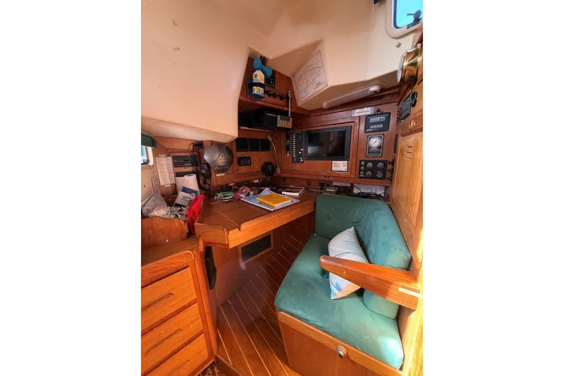 Slide: The Image of Cozy 1993 Tartan 4600 yacht interior with navigation station and green cushioned seating. - 21