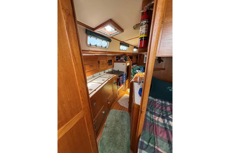 Slide: The Image of Interior of 1993 Tartan 4600 sailboat, featuring cozy wood cabinetry and compact kitchen area. - 21