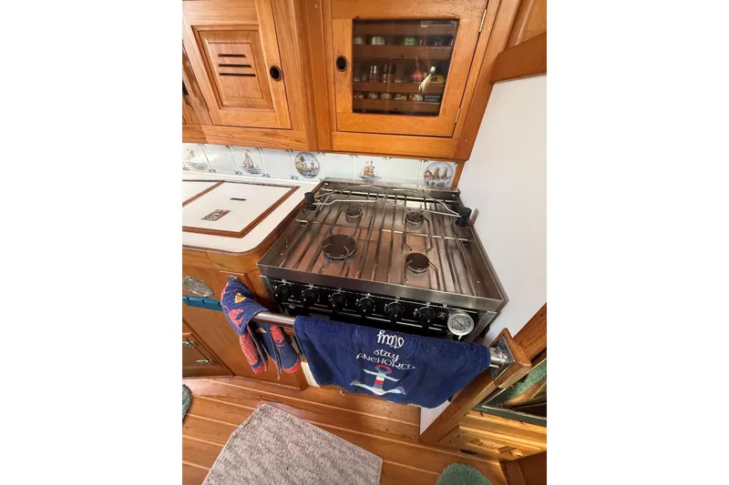 Slide: The Image of 1993 Tartan 4600 yacht kitchen with stove, wooden cabinets, and nautical-themed decor. - 23