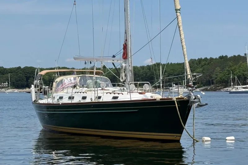 The Image of Sailboat Tartan 4600, 1993 model, anchored in a serene bay with forested shoreline. - 0