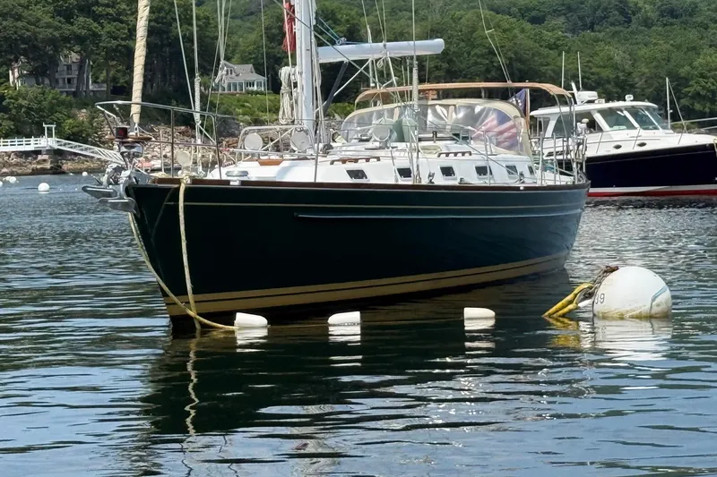 Slide: The Image of Sailboat Tartan 4600 (1993) moored in a scenic harbor with lush greenery. - 1