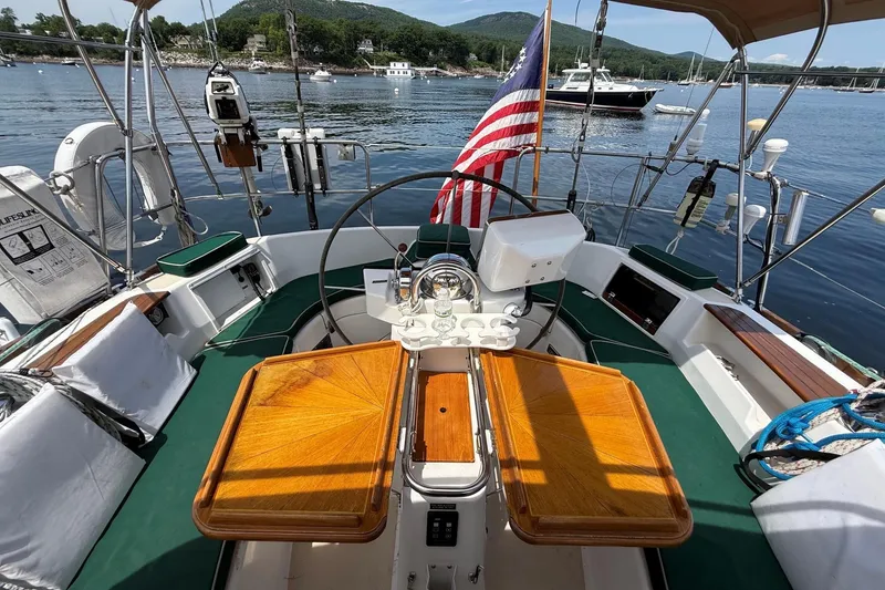 Slide: The Image of Cockpit of a 1993 Tartan 4600 sailboat with wooden tables and American flag. - 13