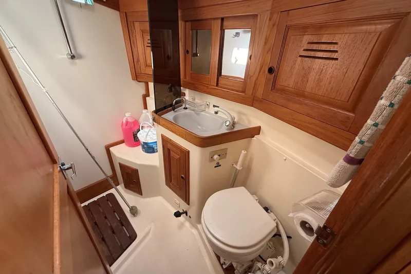 Slide: The Image of 1993 Tartan 4600 yacht bathroom with wooden cabinets, sink, and marine toilet. - 46