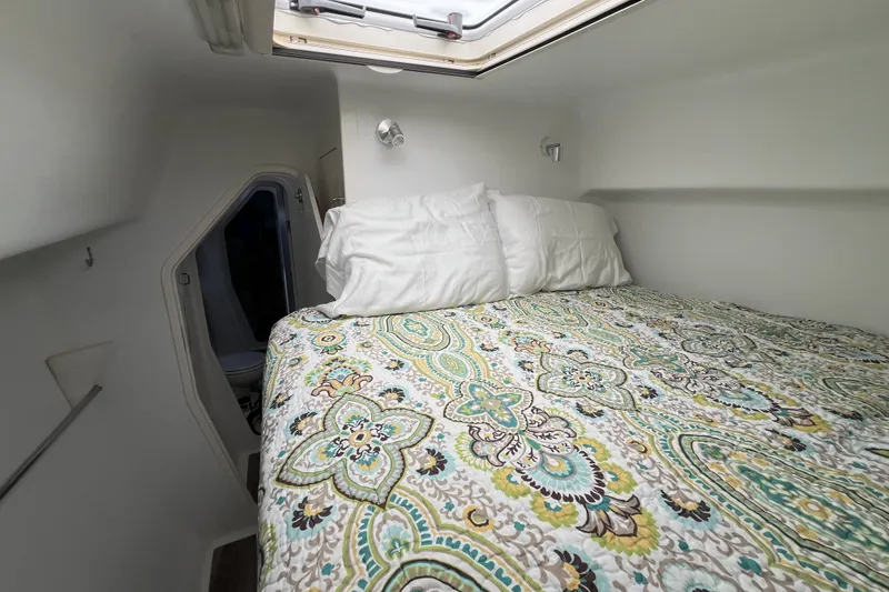 Slide: The Image of Cozy cabin bedroom in a 2002 Voyage 440 yacht with patterned bedding and overhead hatch. - 32