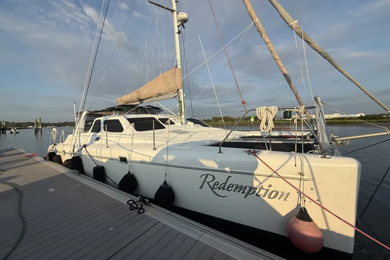 The Image of 2002 Voyage 440 catamaran named "Redemption" docked at a marina under a clear sky. - 0