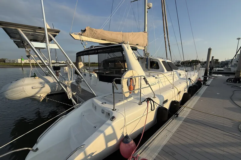 Slide: The Image of 2002 Voyage 440 catamaran docked at marina, featuring sleek design and spacious deck. - 5