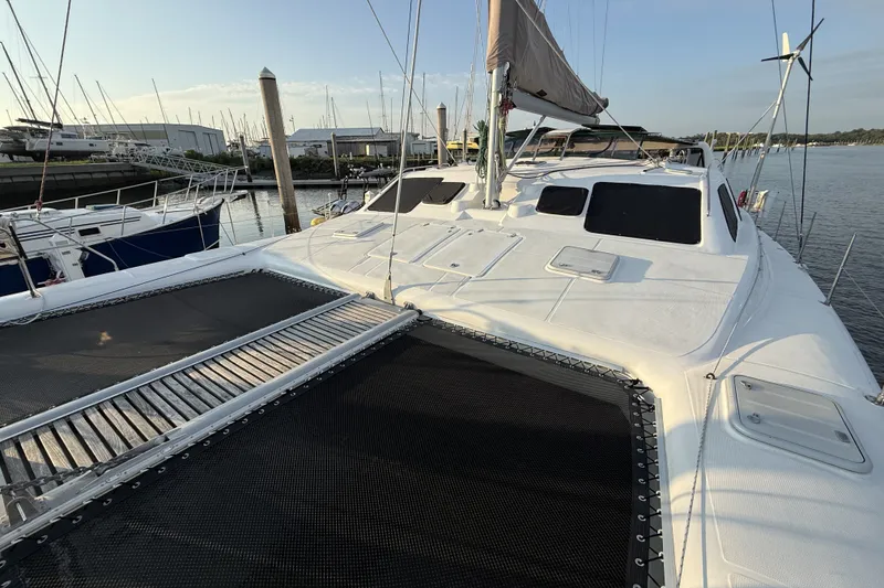 Slide: The Image of 2002 Voyage 440 catamaran docked at marina, featuring spacious deck and netting. - 9