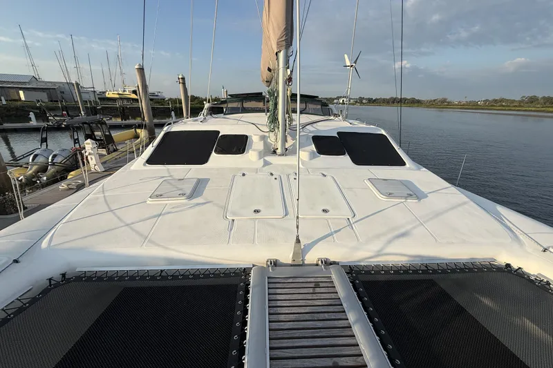 Slide: The Image of 2002 Voyage 440 catamaran docked, showcasing spacious deck and sleek design. - 11